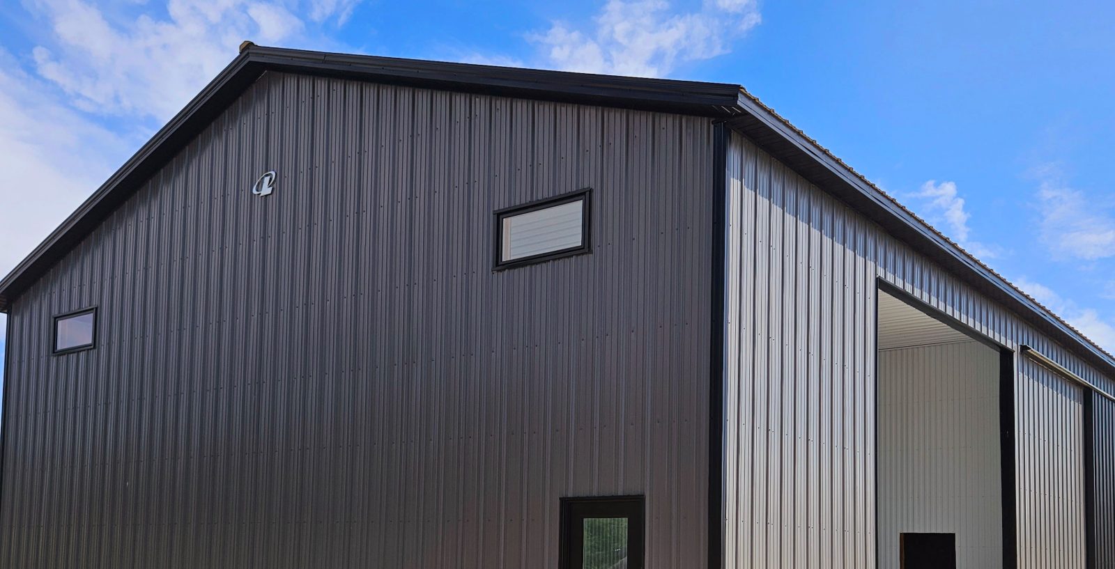 Custom agricultural post-frame machine shed with dark metal siding